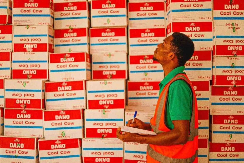 pekerja gudang sedang melakukan inventory control disebelah tumpukan kardus